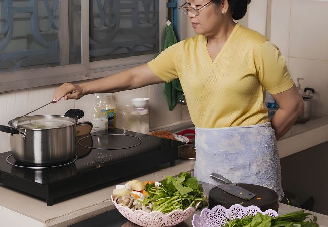 Người giúp việc chăm sóc trẻ em đang nấu ăn và chuẩn bị bữa ăn trong gia đình
