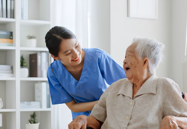 Người chăm sóc người cao tuổi trò chuyện và hỗ trợ cụ bà trong sinh hoạt hằng ngày
